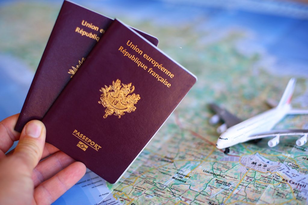 french passports on top of a map with a toy plane