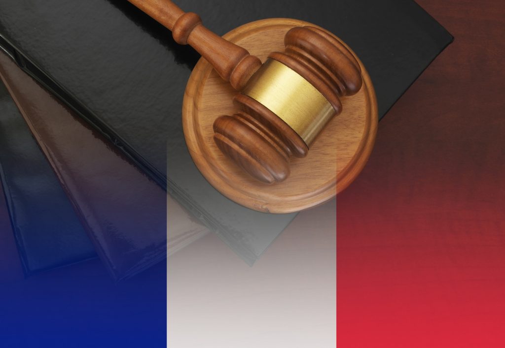 A gavel resting on its stand over a graphic of a French flag.
