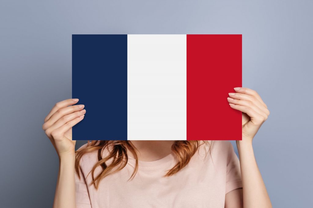 A person holding up a paper with the french flag on it