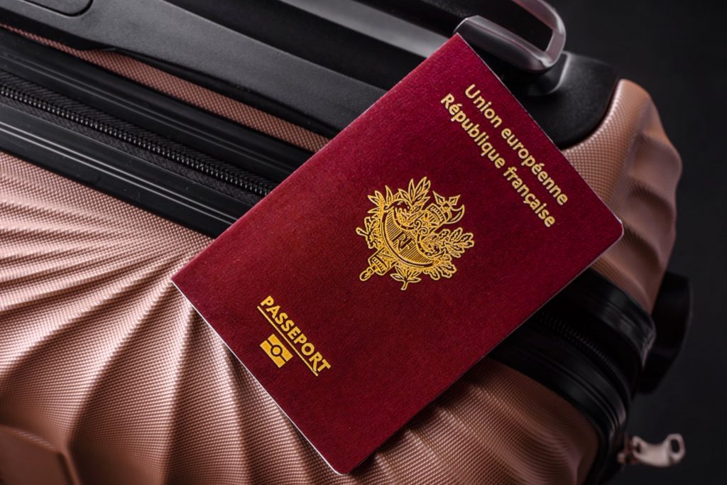 French passport on top of a pink suitcase